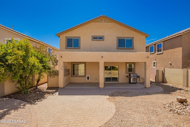 rear view of house featuring a patio area, a fenced backyard, and stucco siding