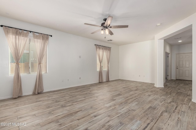 empty room featuring visible vents, light wood-style flooring, baseboards, and ceiling fan