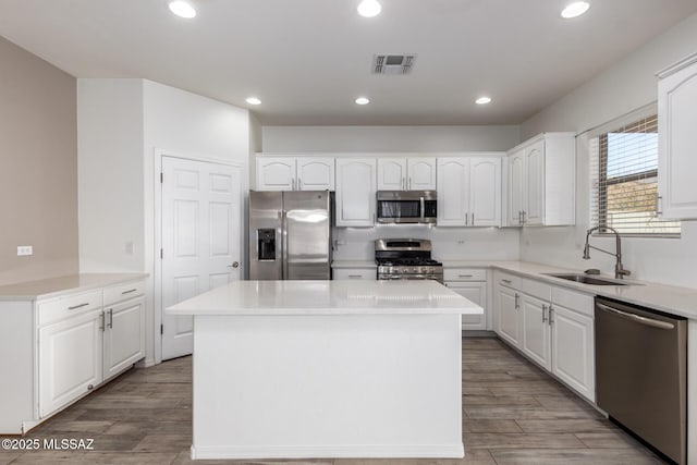 kitchen featuring white cabinets, stainless steel appliances, a center island, a sink, and visible vents