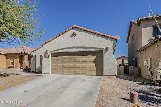 mediterranean / spanish home with concrete driveway, an attached garage, a tile roof, and stucco siding