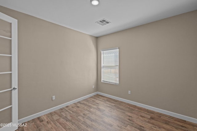 empty room with baseboards, wood finished floors, and visible vents