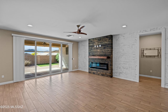 unfurnished living room with ceiling fan, baseboards, wood finished floors, and a fireplace
