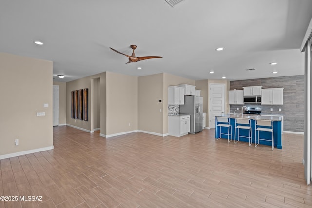 unfurnished living room with light wood-style flooring, baseboards, recessed lighting, and ceiling fan