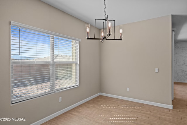 unfurnished dining area featuring a chandelier, wood finished floors, and baseboards