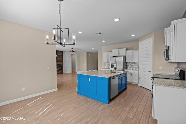 kitchen with blue cabinets, white cabinets, baseboards, appliances with stainless steel finishes, and visible vents