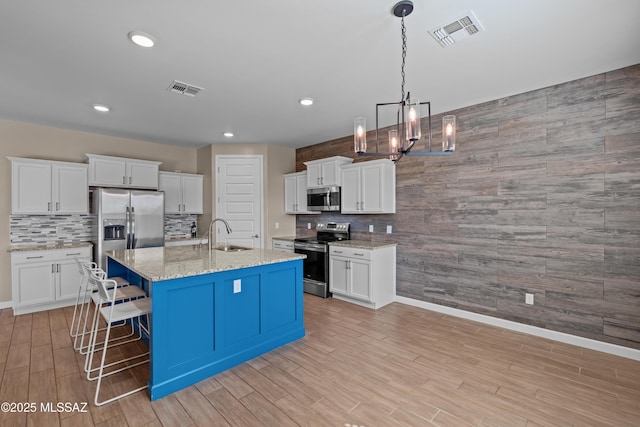 kitchen featuring stainless steel appliances, a sink, baseboards, visible vents, and a chandelier