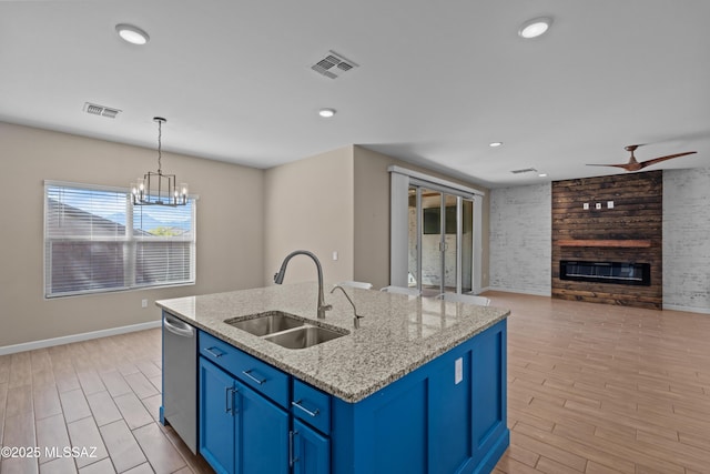 kitchen featuring dishwasher, blue cabinetry, a sink, and visible vents