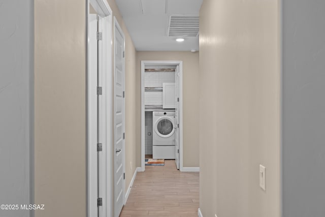 hall with attic access, light wood-style floors, baseboards, washer / clothes dryer, and visible vents