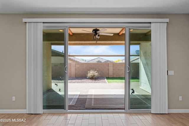 doorway with baseboards, a ceiling fan, and wood finished floors