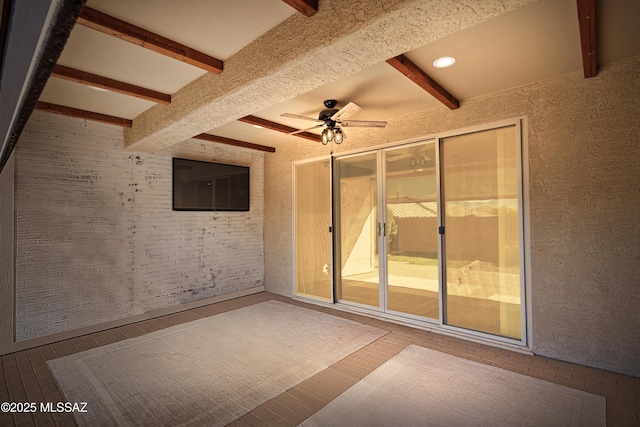 unfurnished room featuring beamed ceiling and ceiling fan