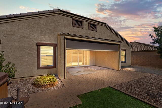 back of house with fence, a patio, and stucco siding