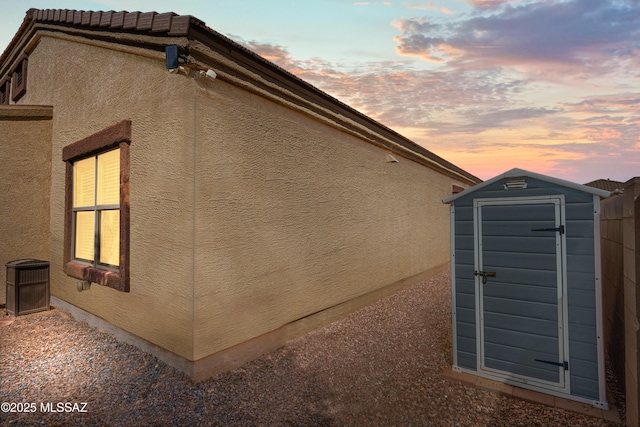 view of home's exterior with a storage unit, an outdoor structure, and stucco siding