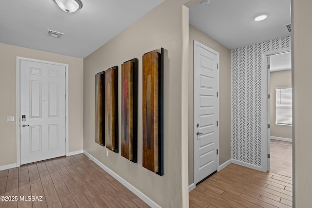 hallway featuring baseboards, wood finished floors, and visible vents