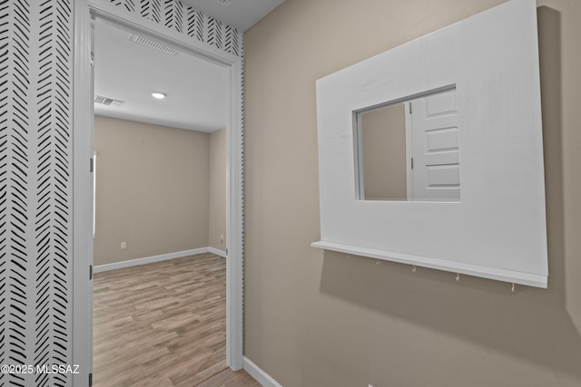 hall with baseboards, wood finished floors, and visible vents