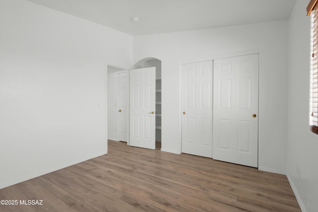 2145 N Horseshoe Trl, Tucson, AZ 85745 - unfurnished bedroom featuring arched walkways, wood finished floors, baseboards, and a closet