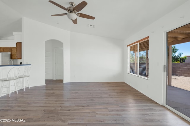2145 N Horseshoe Trl, Tucson, AZ 85745 - unfurnished living room with arched walkways, ceiling fan, and light wood-type flooring