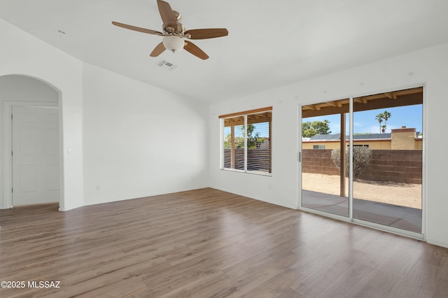 2145 N Horseshoe Trl, Tucson, AZ 85745 - empty room with wood finished floors, ceiling fan, arched walkways, and vaulted ceiling