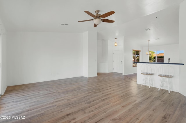 2145 N Horseshoe Trl, Tucson, AZ 85745 - unfurnished living room with ceiling fan, wood finished floors, a sink, and a chandelier