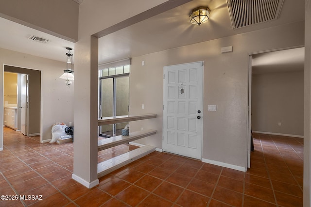 entryway with baseboards, visible vents, and dark tile patterned floors