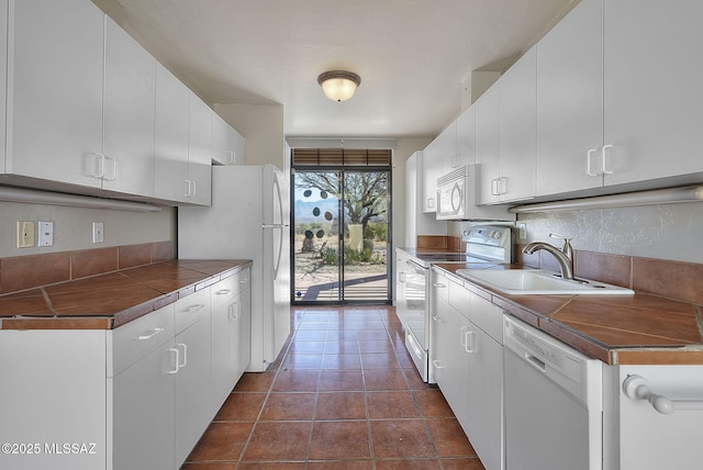 kitchen featuring a sink, dark countertops, white cabinetry, white appliances, and dark tile patterned flooring