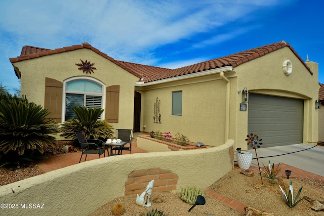 mediterranean / spanish-style house featuring an attached garage, a tile roof, stucco siding, and driveway