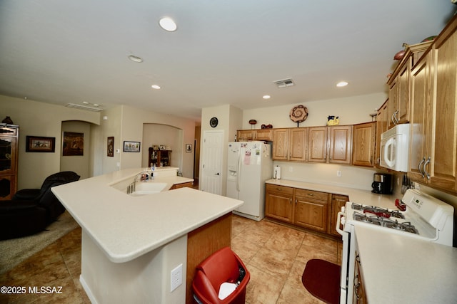 kitchen with brown cabinets, light tile patterned flooring, a kitchen island with sink, white appliances, and visible vents