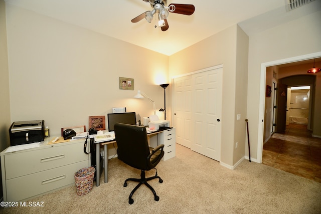 carpeted office space featuring baseboards, visible vents, and ceiling fan