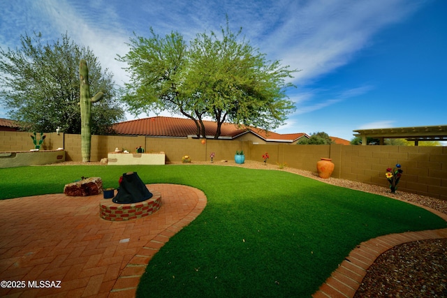 view of yard with a fire pit, a fenced backyard, and a patio
