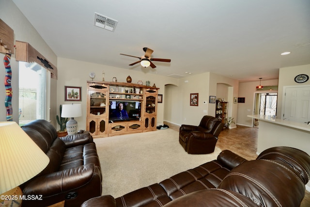 living area featuring arched walkways, a ceiling fan, visible vents, and plenty of natural light