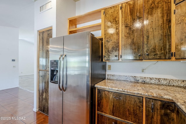 kitchen with tile patterned floors, visible vents, light stone counters, and stainless steel fridge with ice dispenser