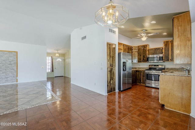 kitchen with stainless steel appliances, a sink, visible vents, lofted ceiling, and ceiling fan with notable chandelier