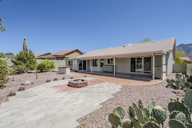 back of house featuring fence, stucco siding, a tile roof, a patio, and an outdoor fire pit