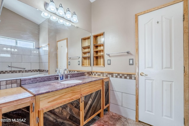 full bath with wainscoting, vanity, and tile walls