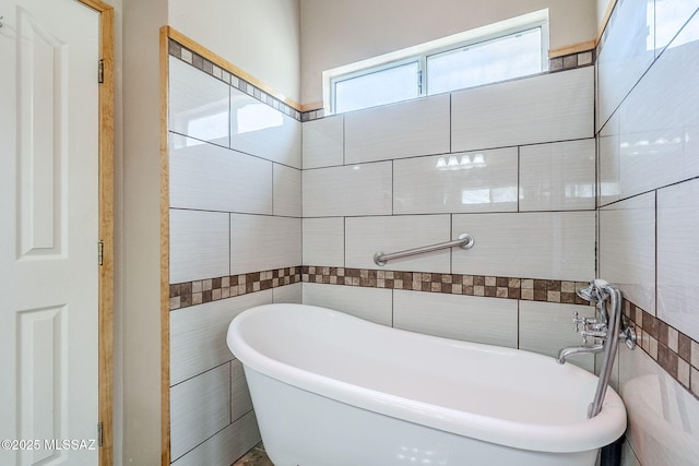 full bath with tile walls and a freestanding tub