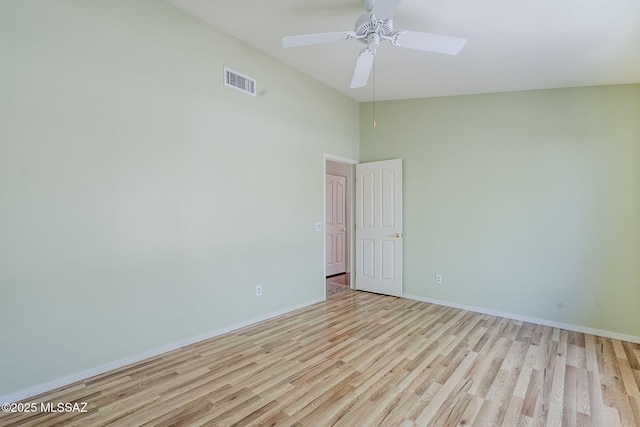 empty room with a towering ceiling, wood finished floors, visible vents, baseboards, and ceiling fan