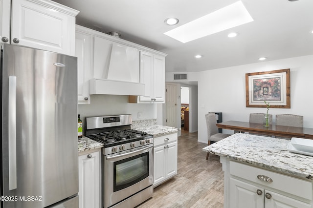 889 Paseo Los Mochis Unit 10, Rio Rico, AZ 85648 - kitchen featuring white cabinets, recessed lighting, a skylight, appliances with stainless steel finishes, and custom range hood