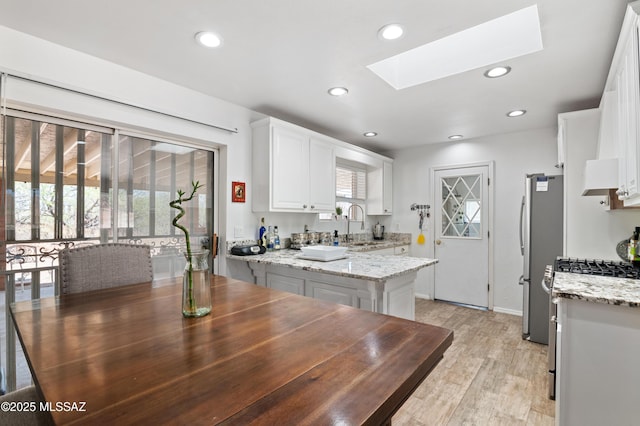 889 Paseo Los Mochis Unit 10, Rio Rico, AZ 85648 - kitchen with white cabinets, recessed lighting, a sink, a skylight, and light wood-style flooring