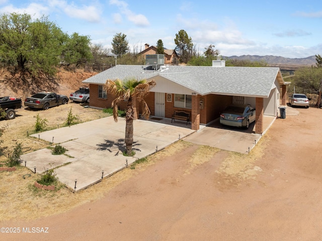 889 Paseo Los Mochis Unit 10, Rio Rico, AZ 85648 - view of front facade with a carport, a shingled roof, driveway, and a mountain view