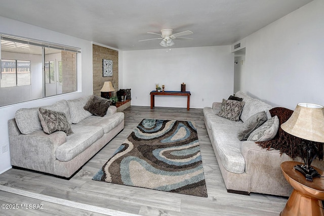living room featuring a ceiling fan, visible vents, and wood finished floors