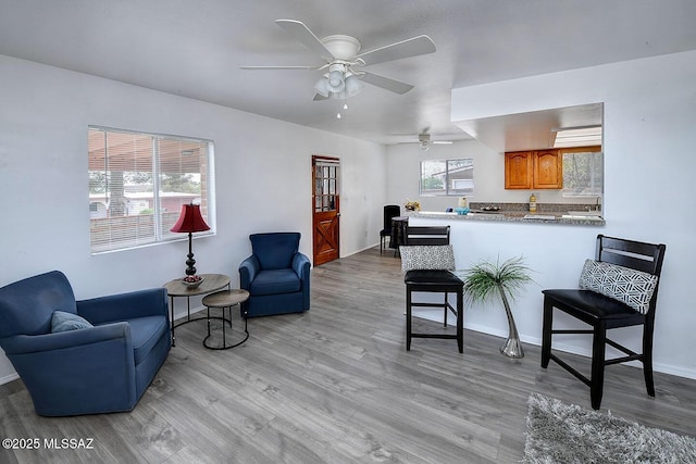 interior space featuring baseboards, a ceiling fan, and light wood-style floors