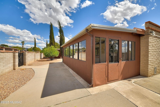 view of side of home featuring a sunroom, a patio, and fence