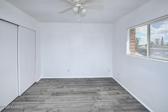 unfurnished bedroom featuring wood finished floors, a ceiling fan, baseboards, and a closet