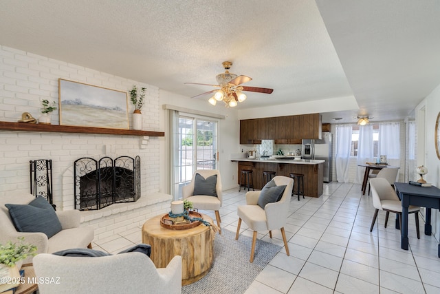 living room with light tile patterned floors, ceiling fan, a textured ceiling, and a fireplace