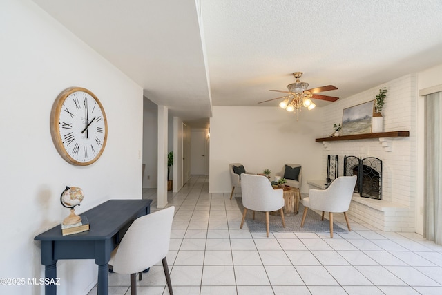 living area with a fireplace, a textured ceiling, a ceiling fan, and light tile patterned floors