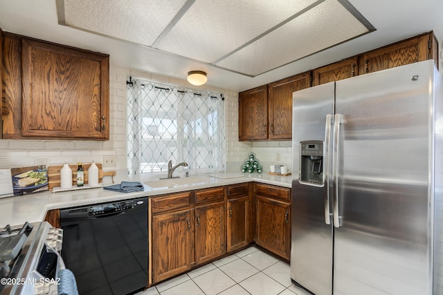 kitchen featuring a sink, stainless steel appliances, light tile patterned floors, tasteful backsplash, and light countertops