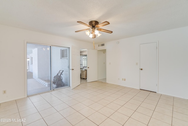 empty room with light tile patterned floors, visible vents, ceiling fan, and baseboards