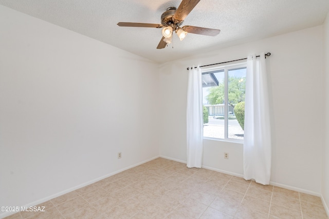 empty room featuring a textured ceiling, a ceiling fan, and baseboards