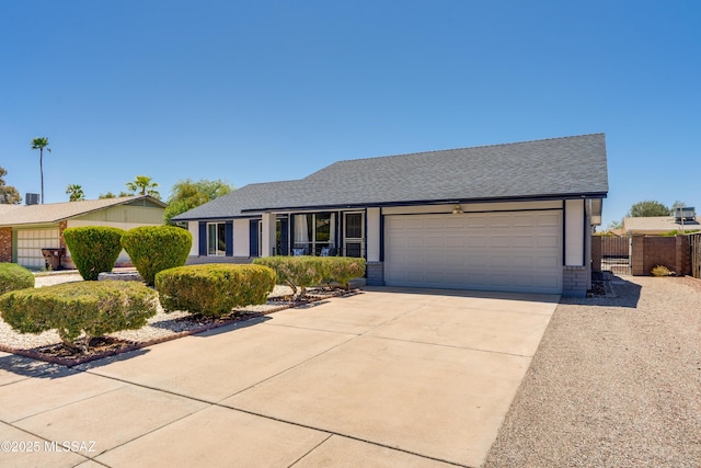 ranch-style home with fence, roof with shingles, driveway, and an attached garage