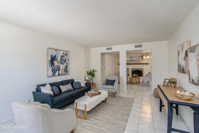 living area with visible vents, a textured ceiling, light tile patterned flooring, and a fireplace