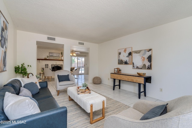 living room with light tile patterned flooring, visible vents, a ceiling fan, and a fireplace
